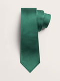 Emerald green silk necktie rolled into a loose coil on a cream background.