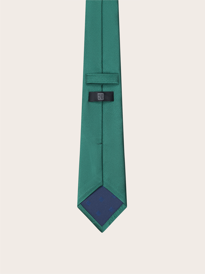 Emerald green silk necktie with a navy tip, showing the back keeper loop and brand label.