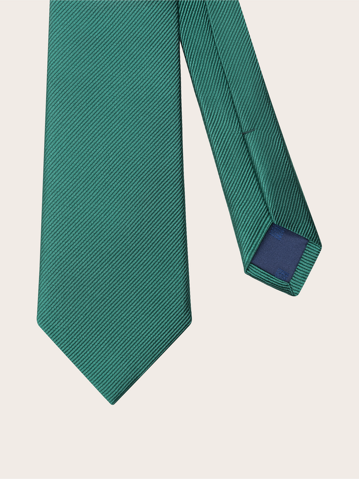 Emerald green silk necktie draped at an angle, revealing its navy tip and brand label.