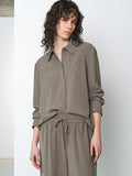 Woman wearing a long sleeve khaki pinstripe shirt with matching trousers