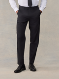 Man from waist down wearing black suit trousers, with a black tie visible above.