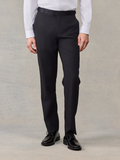 Man from waist down wearing black tuxedo trousers with a satin waistband trim.