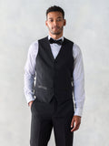 Man in a black tuxedo vest with a black bow tie and matching trousers.