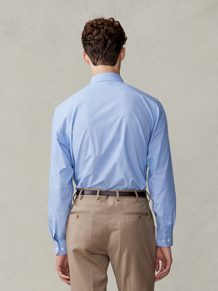 Back view of a man in a light blue dress shirt and beige trousers.