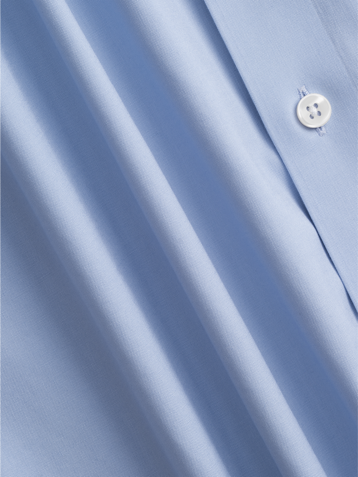 Close-up of light blue dress shirt fabric with folds and a button.