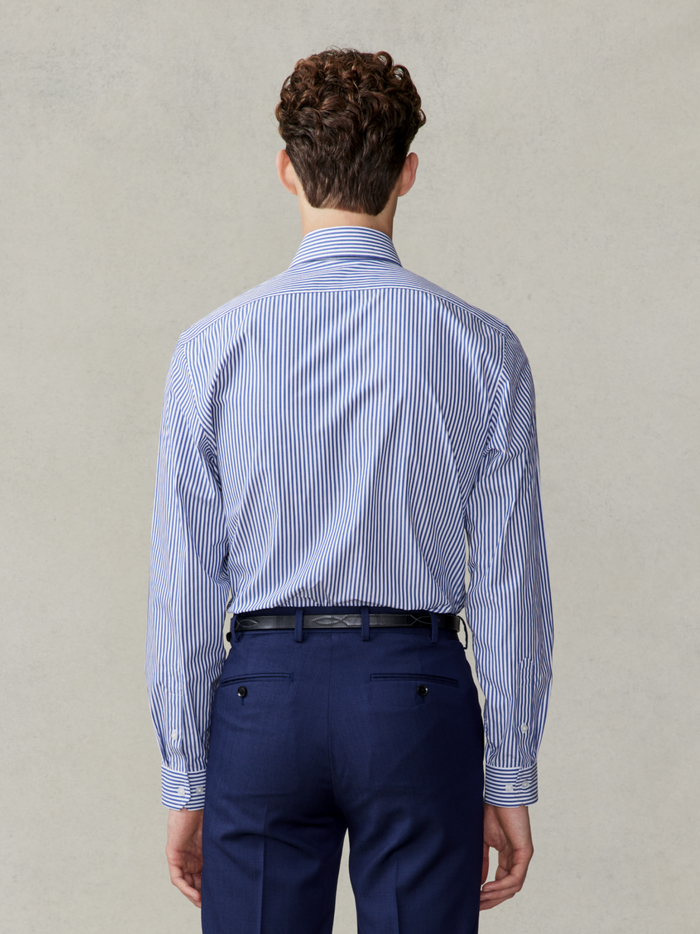 Back view of a man in a navy striped dress shirt and navy trousers.