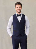 Smiling man in a navy tuxedo vest with a black bow tie and matching trousers.