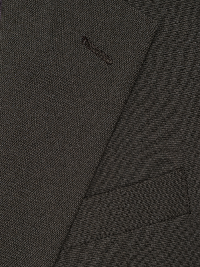 Close-up of olive suit lapel with welt pocket detail.