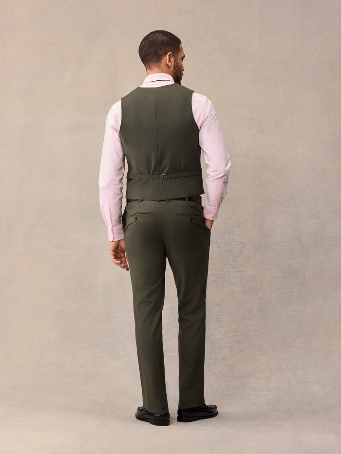 Back view of a man in an olive suit vest and trousers, full length.