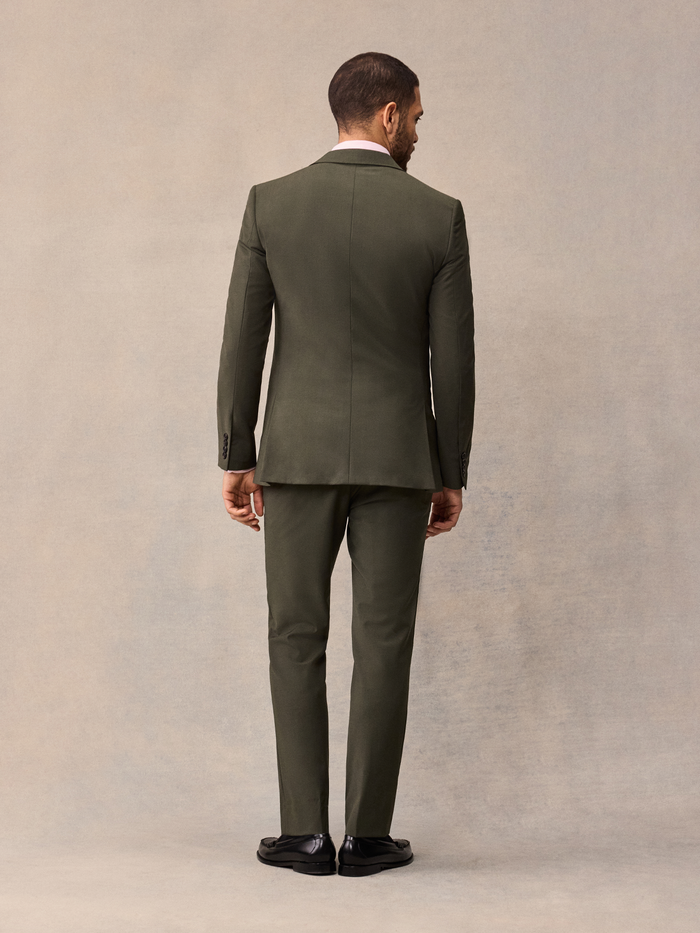 Back view of a man in an olive suit jacket and trousers.