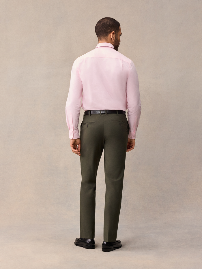 Back view of a man in a pink dress shirt and olive trousers.