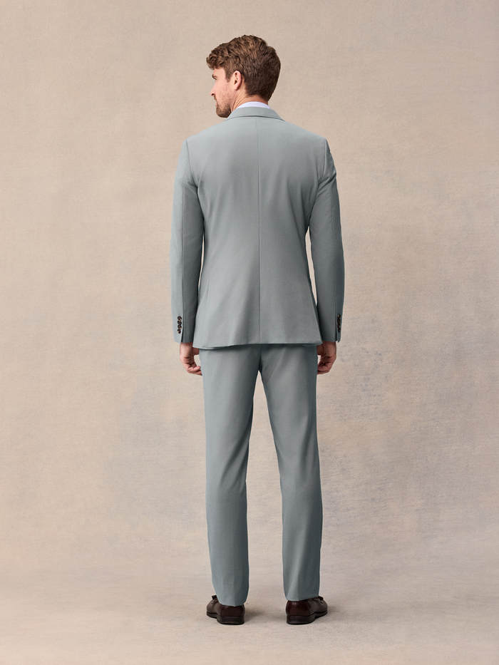 Back view of a man in a sage suit jacket and trousers.