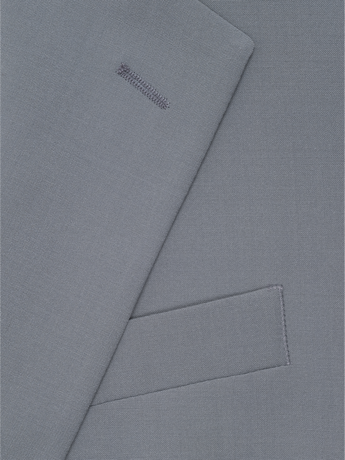 Close-up of sage suit fabric with folded lapel and pocket detail.