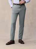 Man from waist down wearing sage suit trousers with a brown belt.