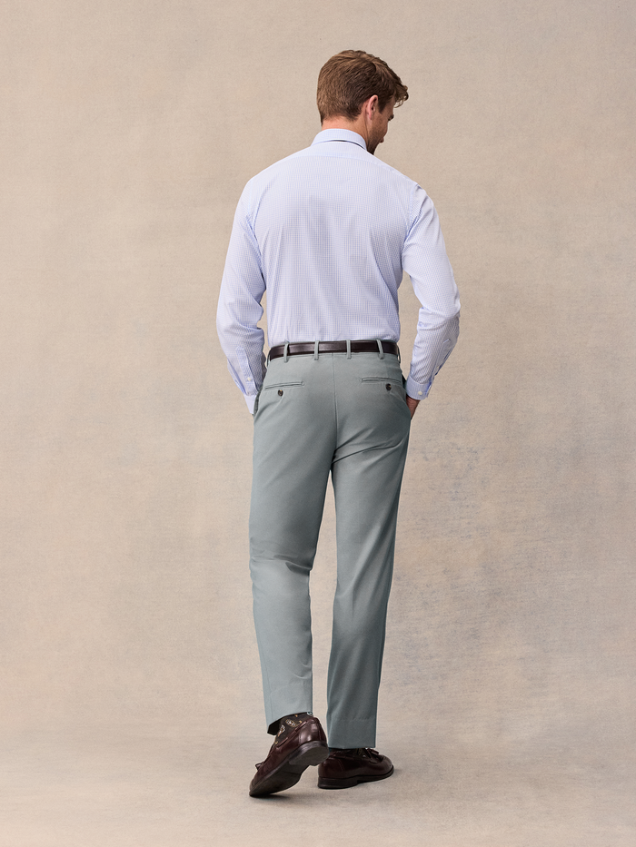 Back view of a man walking in a checked shirt and sage trousers.