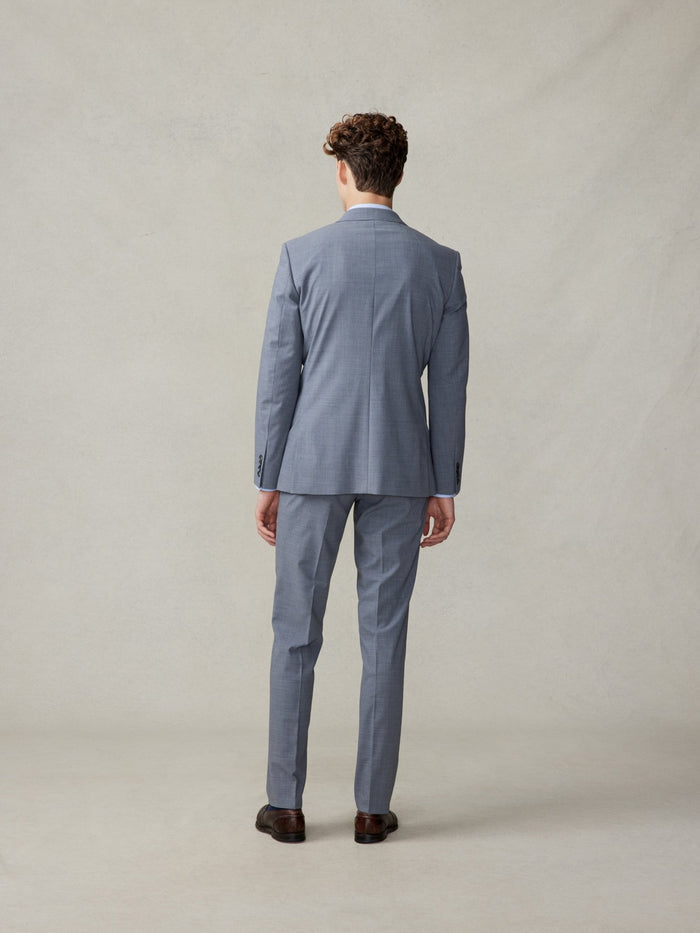 Back view of a man in a slate grey suit, full length.