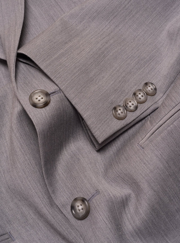 Close-up of sterling grey suit cuff buttons and folded sleeve fabric.