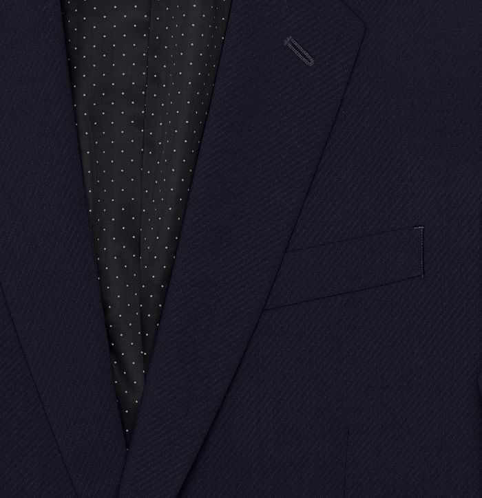 Close-up of a true navy suit lapel with polka-dot lining and chest pocket.