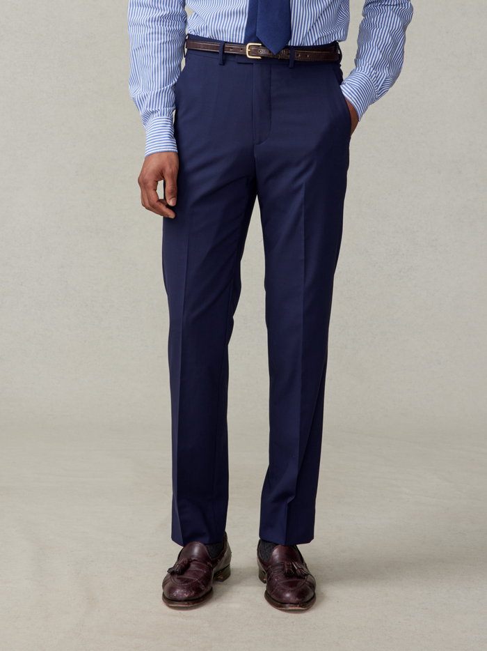 Man from waist down in true navy suit trousers, a striped shirt, and brown loafers.