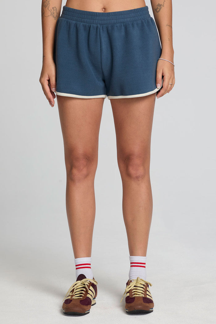 Front view of a woman wearing the Chaser  Eyla Dark Denim Shorts on a neutral background with sneakers