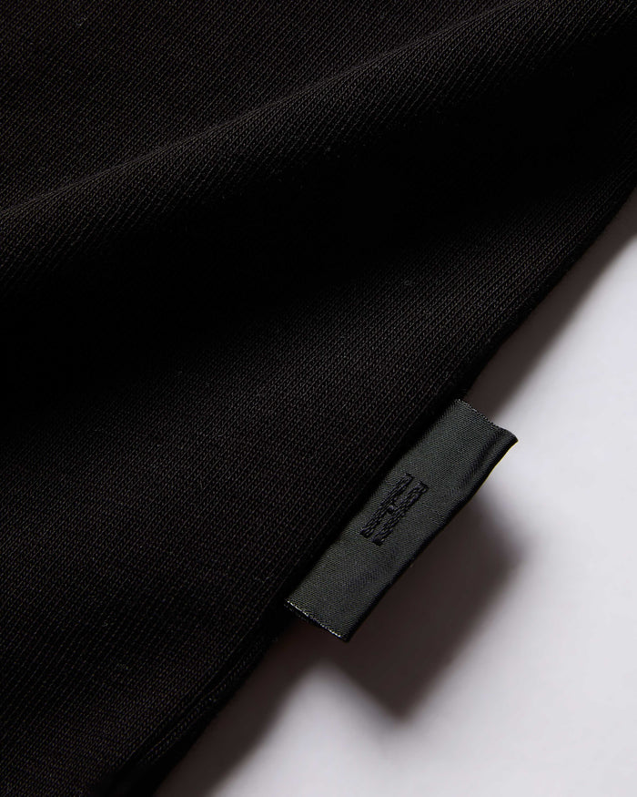 Close-up of a black garment with a brand label on a white background