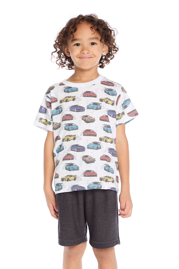 Boy wearing the Chaser Kids Fast Cars Tee in white with all-over colorful car graphics on a white background