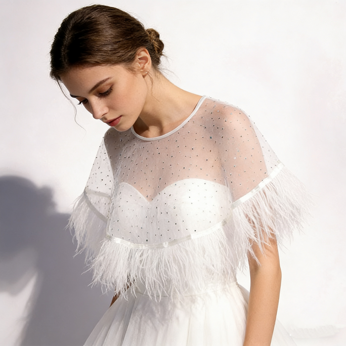 Bride wearing a sheer feather bridal cape over a wedding gown during an elegant bridal portrait and ceremony.