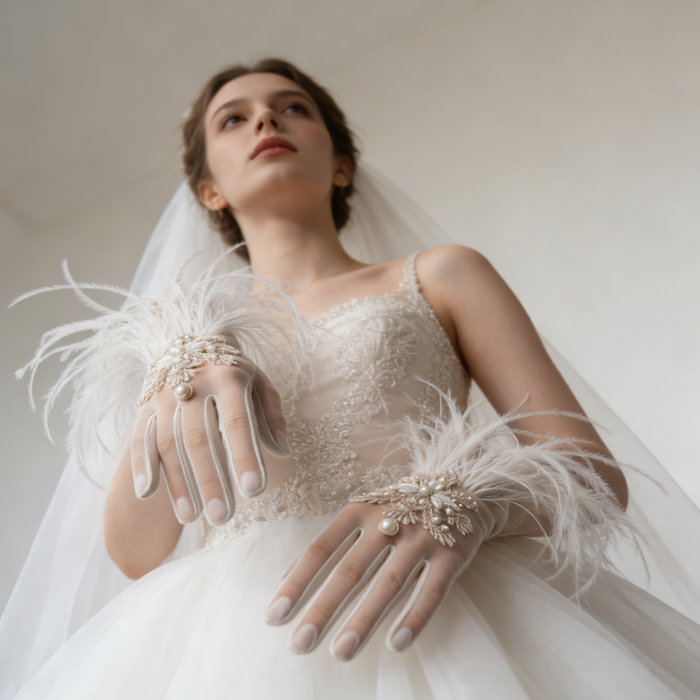 Bride wearing feather trimmed bridal gloves with pearl embroidery and a lace wedding gown during an elegant bridal photoshoot.