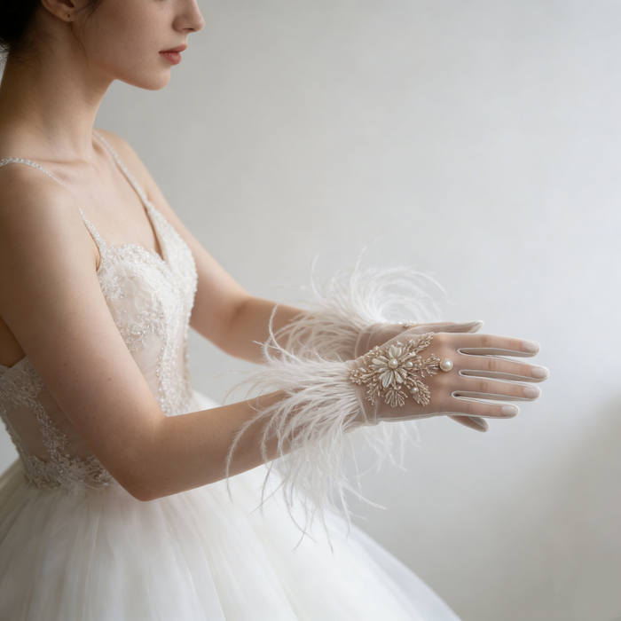 Bride wearing feather trimmed bridal gloves with pearl embroidery and a lace wedding gown during an elegant bridal photoshoot.