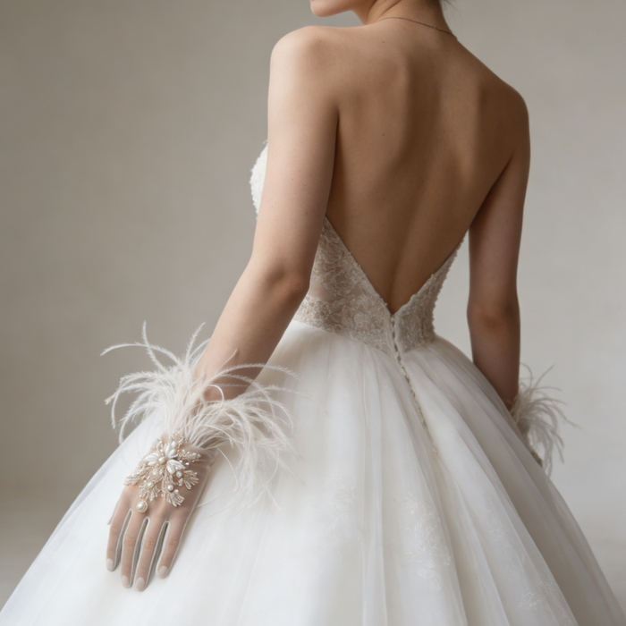 Bride wearing feather trimmed bridal gloves with pearl embroidery and a lace wedding gown during an elegant bridal photoshoot.
