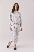 Full body view of woman wearing Chaser’s Festive Stars Pullover in Light Grey with star patterns and matching Festive Stars Joggers on a white background