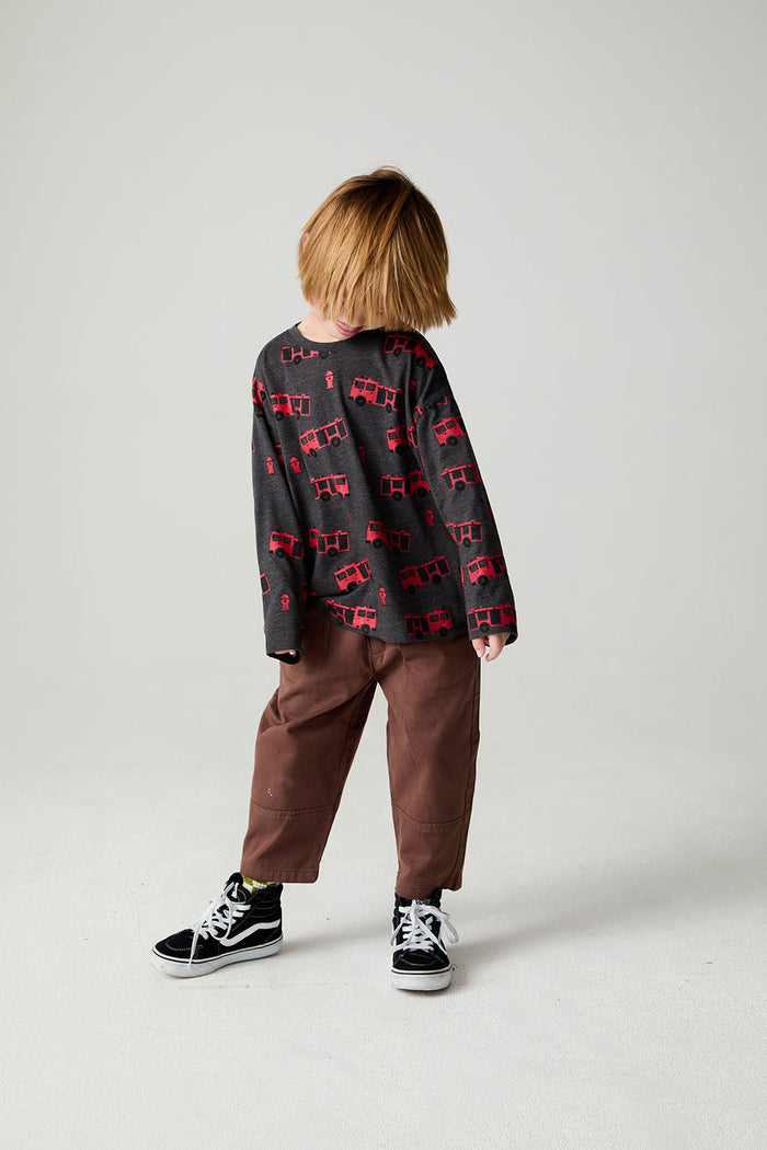 A full body front view of a boy wearing the Chaser Fire Trucks Boys Tee on a neutral background