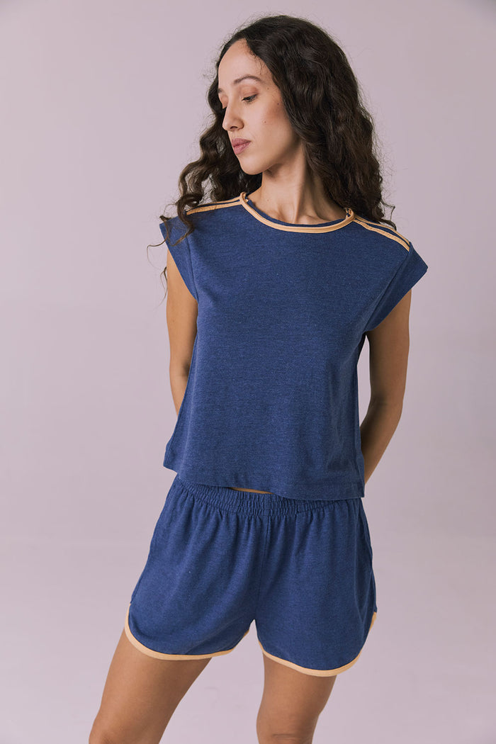 Front-facing studio image of the Chaser Flora Cropped Honest Indigo Cap Sleeve Crewneck Tee styled with matching Taylorr Honest Indigo Blue Shorts showing contrast tan trim and relaxed drape
