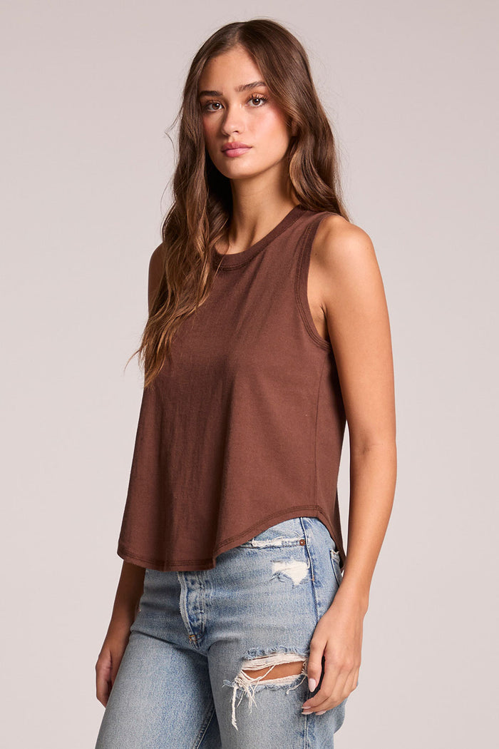 Side angle view of a woman wearing the Chaser  Flouncy Kahlua Muscle Tank on a neutral background with arms at her sides