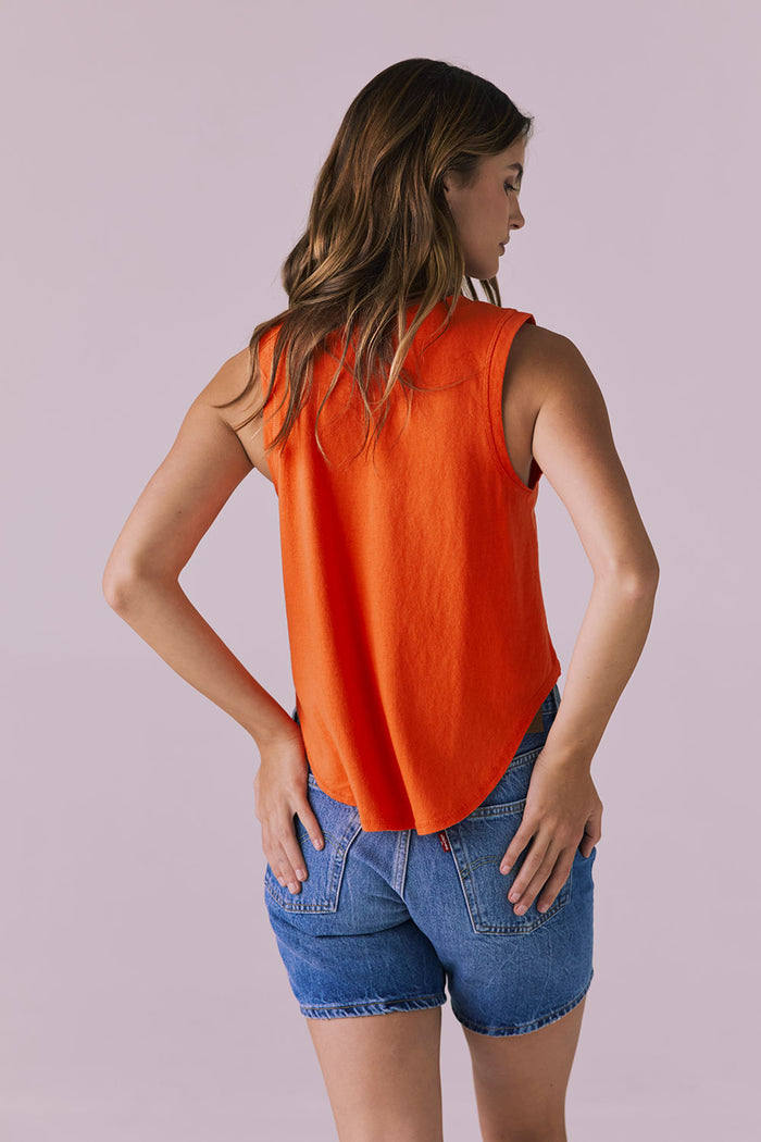 Back studio image of the Chaser Flouncy Neon Flare Muscle Tank paired with denim shorts highlighting the rounded back hemline and relaxed movement