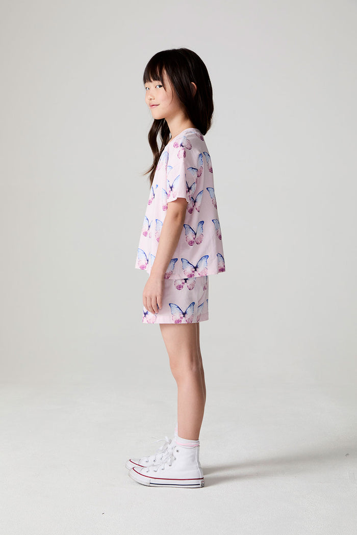 Full body side view of a girl wearing the Chaser  Flutter Butterfly Shorts and matching shirt on a neutral background
