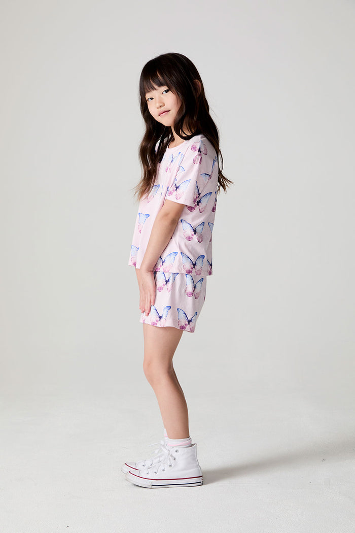 Full body side view of a girl wearing the Chaser Flutter Butterfly Tee on a neutral background