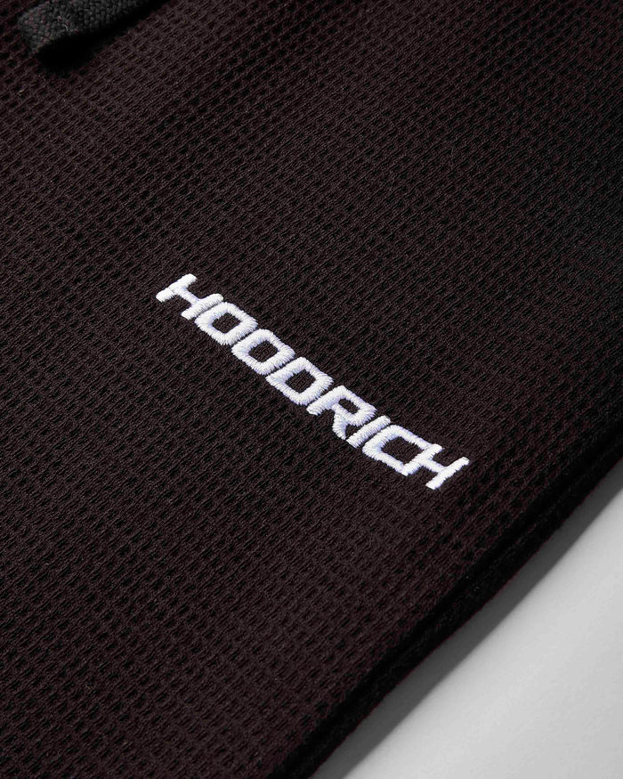 Close-up of a black textured mesh fabric with the brand name 'HOODRICH' printed in white across the center.