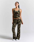 A woman modeling a matching camouflage athletic set consisting of a cropped tank top and high-waisted flared pants, photographed against a light gray studio background.