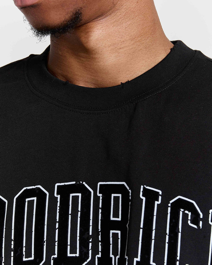 Black t-shirt with white text worn by a person, close-up on neck and shoulders.