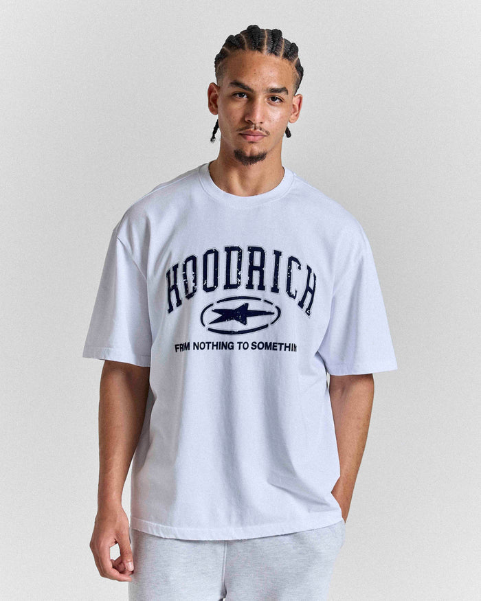 Model wearing a white 'HOODRICH' t-shirt with a star logo and 'FROM NOTHING TO SOMETHING' spell-out on a plain background