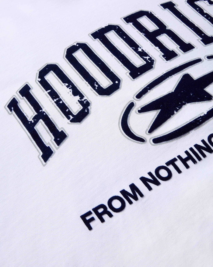 Close-up of dark blue, distressed-effect varsity-style Hoodrich branding and the words 'From Nothing' on a white t-shirt.