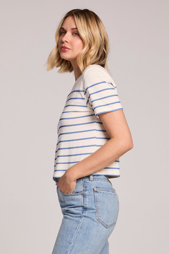 Side view of a woman wearing the Chaser French Riviera Stripe Jameson Tee on a neutral background with her hands in her pockets
