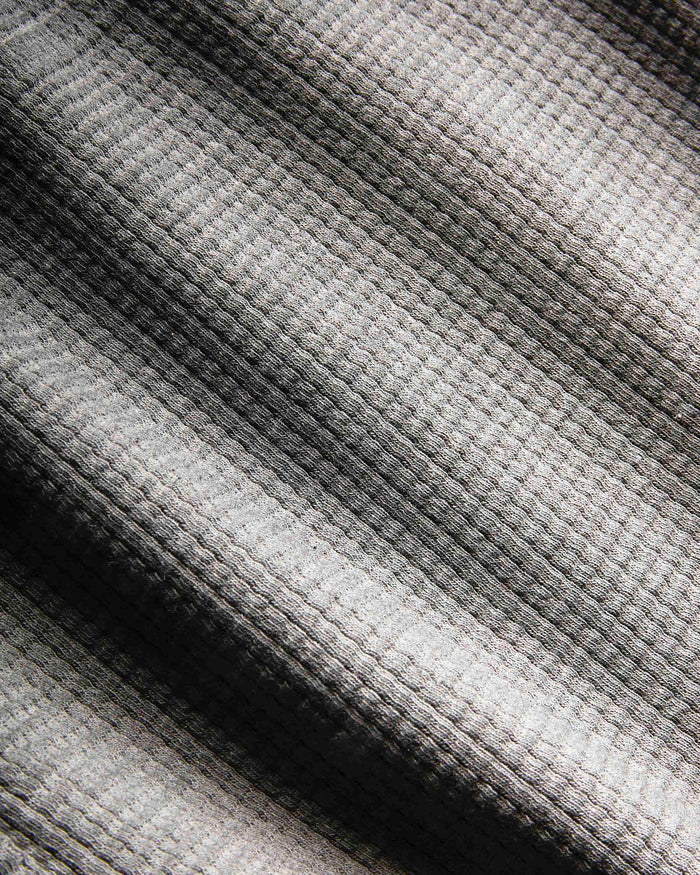 Close-up of a waffle-knit fabric with a striped pattern in shades of gray, black, and off-white.