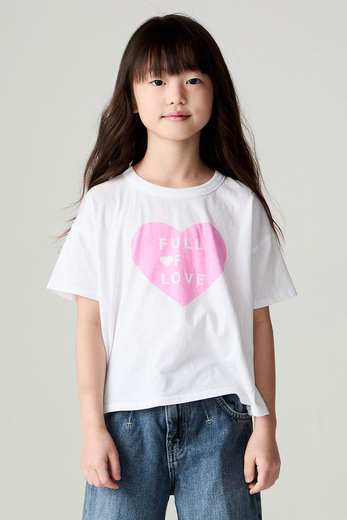 Front view of a girl wearing the Chaser Full Of Love Girls Tee on a neutral background with jeans and hands at sides of body