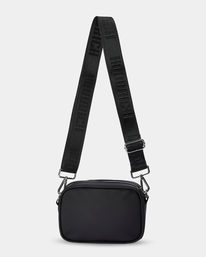 Black crossbody bag with a strap on a light gray background
