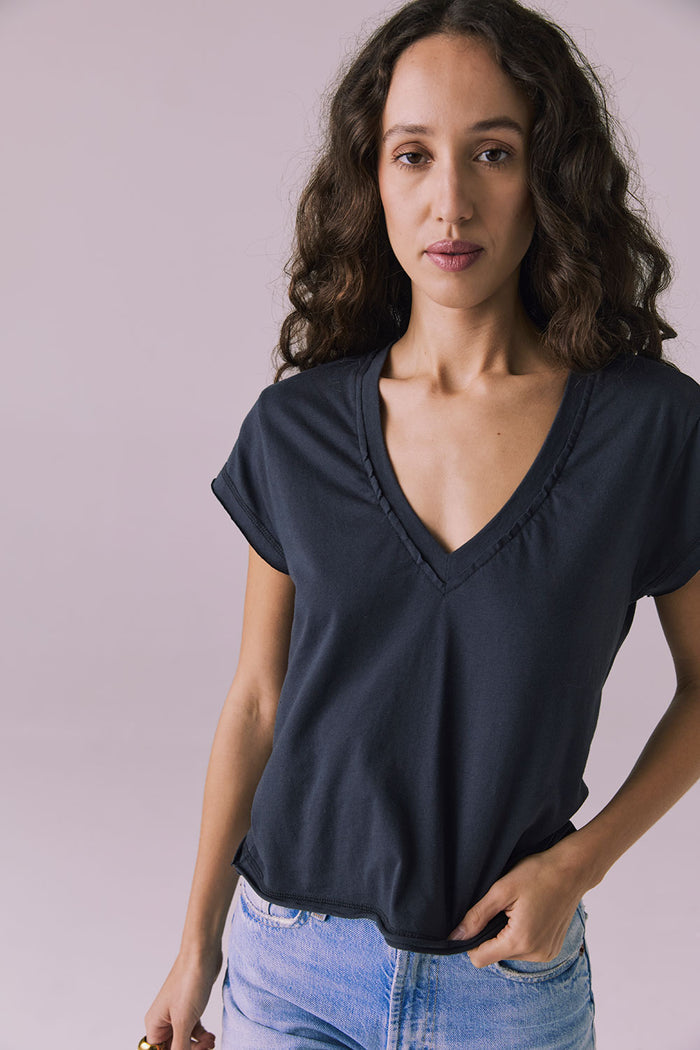 Front studio image of the Chaser Gator V Neck Licorice Black Tee styled with light-wash denim showing deep V neckline and relaxed rolled sleeves