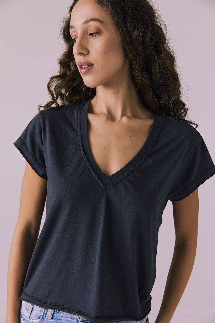 Front-on studio image of the Chaser Gator V Neck Licorice Black Tee with rolled sleeves and soft drape over denim jeans