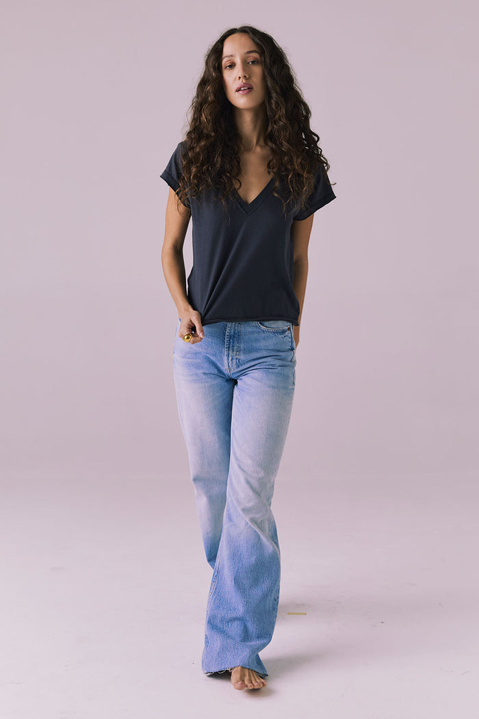 Full-body walking studio image of the Chaser Gator V Neck Licorice Black Tee in Licorice Black paired with light-wash denim for an easy everyday look
