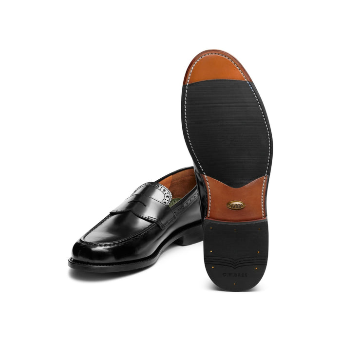 Black leather loafer paired with its tan leather sole, angled view.